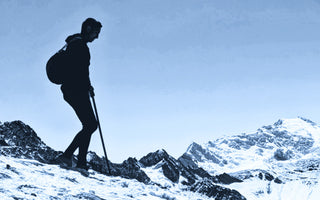 man wearing alpaca outdoor clothing hiking on a snow-covered hill