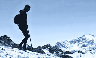 man wearing alpaca outdoor clothing hiking on a snow-covered hill